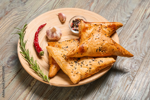 Plate with tasty Uzbek samsa and spices on wooden background photo