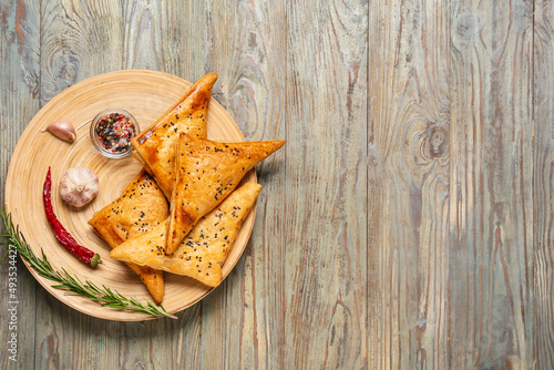 Plate with tasty Uzbek samsa and spices on wooden background