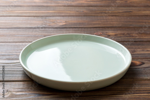 Perspective view of empty blue plate on wooden background. Empty space for your design