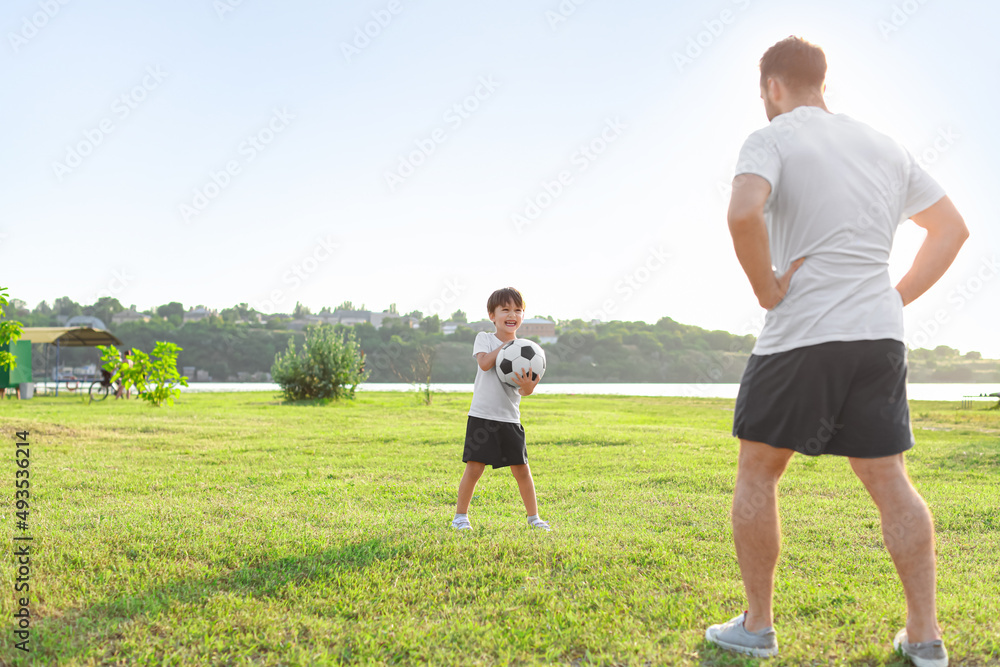 Little boy playing soccer with his father on field Little boy playing soccer with his father on field