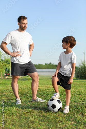 Father and his little son with soccer ball on field