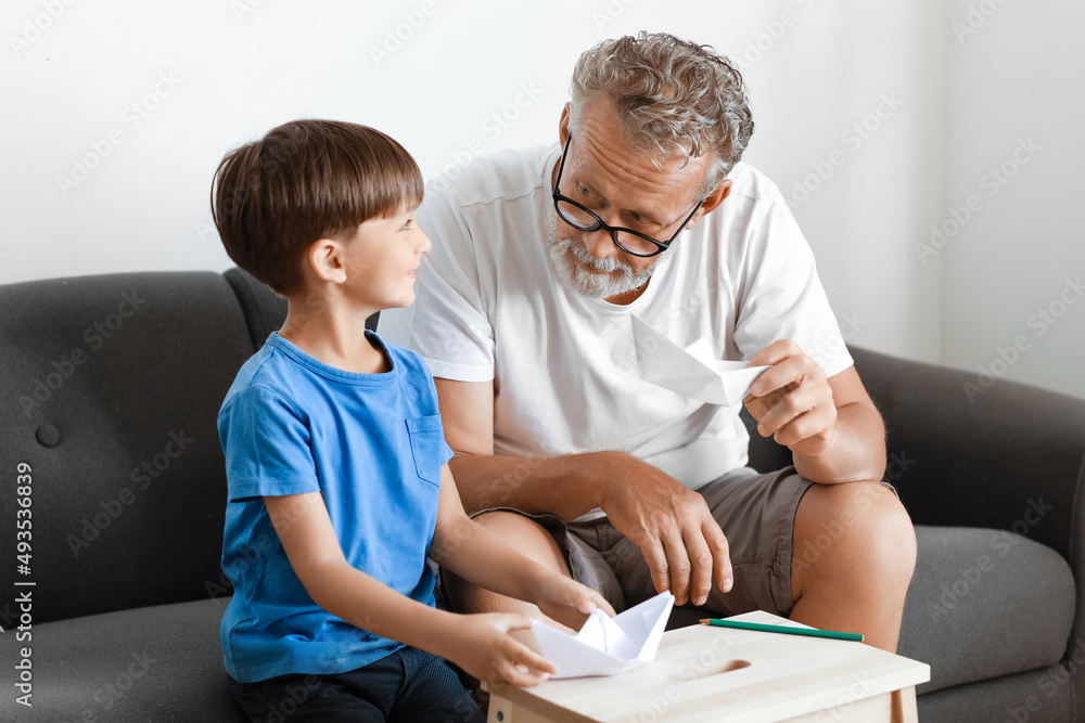 Senior man and his little grandson with paper boats at home Senior man and his little grandson with paper boats at home