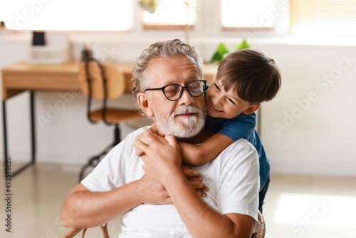 Little boy hugging his grandfather at home photo