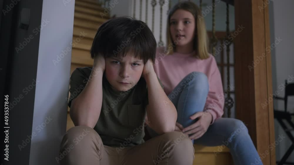 Dissatisfied Caucasian boy closing ears as displeased girl yelling