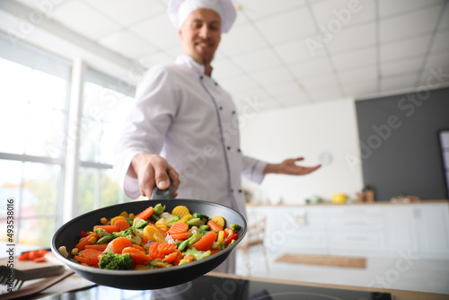 Male chef frying vegetables...