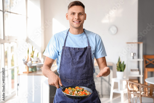 Young man holding frying pa...