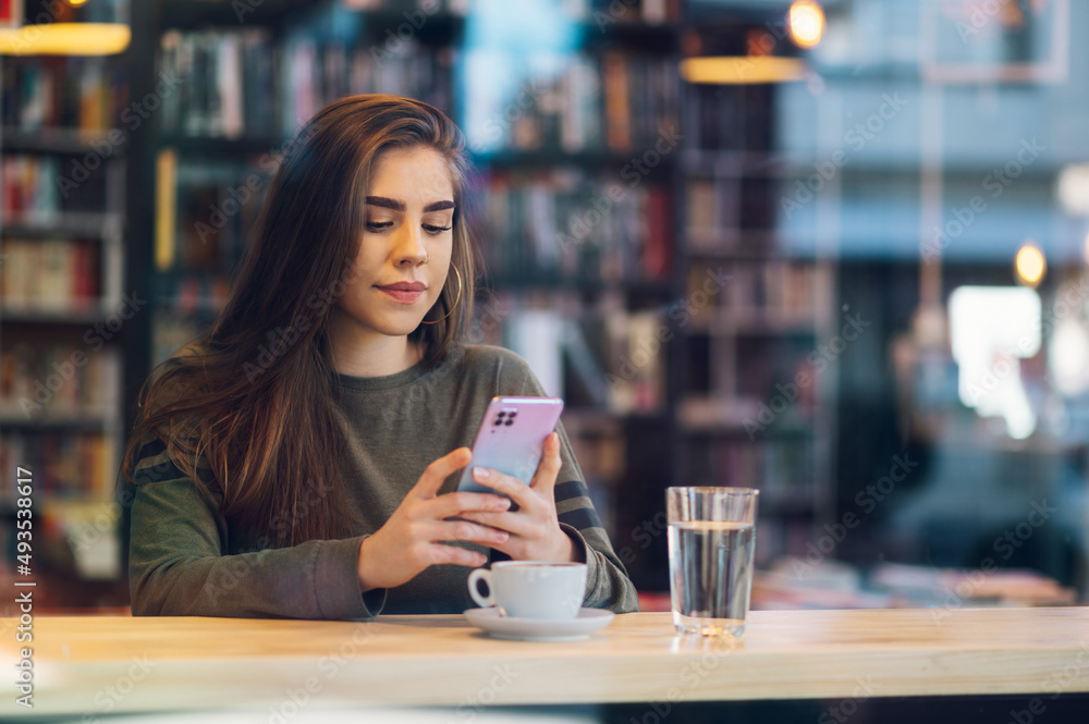 Woman using smartphone and drinking coffee in a cafe. Woman using smartphone and drinking coffee in a cafe.