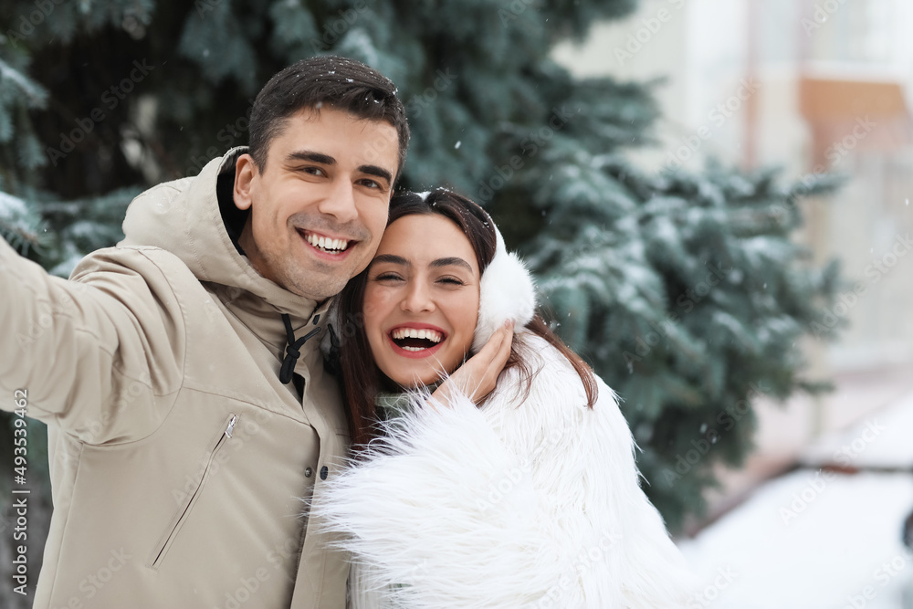 Loving couple taking selfie in park on snowy winter day Loving couple taking selfie in park on snowy winter day