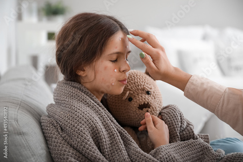 Fotografie Mother applying remedy on skin of her little daughter ill with chickenpox at hom
