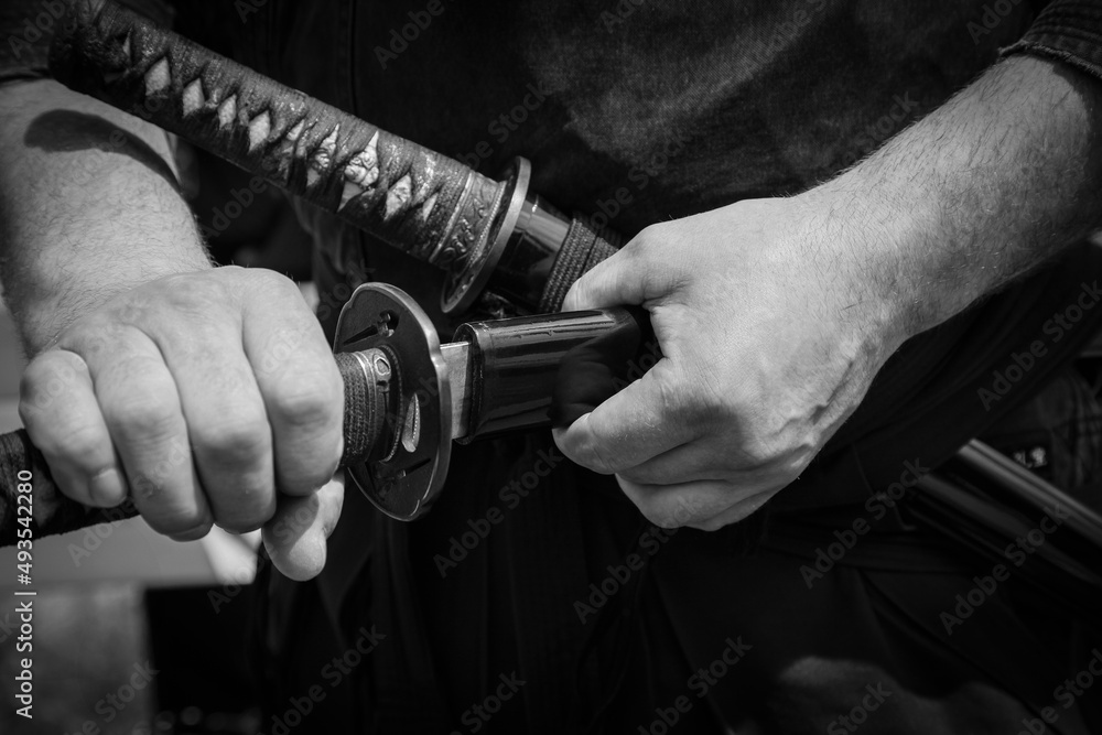 Close up of young martial arts fighter with katana in his hands, black and white.