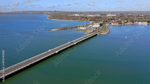 Langstone Bridge over Langstone Harbour which connects the mainland to Hayling Island, the Langstone Sailing Club is on the waterfront of the harbour, Aerial footage.