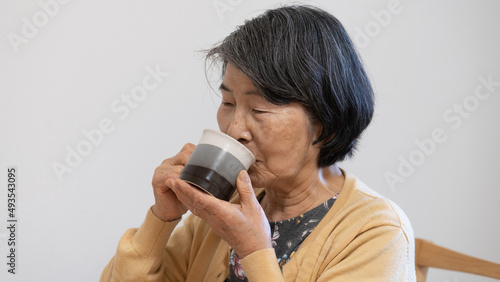 お茶のようにコーヒーを飲む80代の老人女性