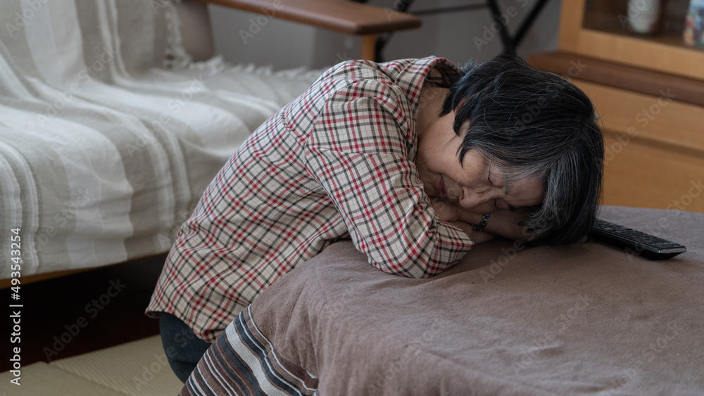 疲れて炬燵でうつ伏せで寝てしまう80代の高齢者女性 疲れて炬燵でうつ伏せで寝てしまう80代の高齢者女性