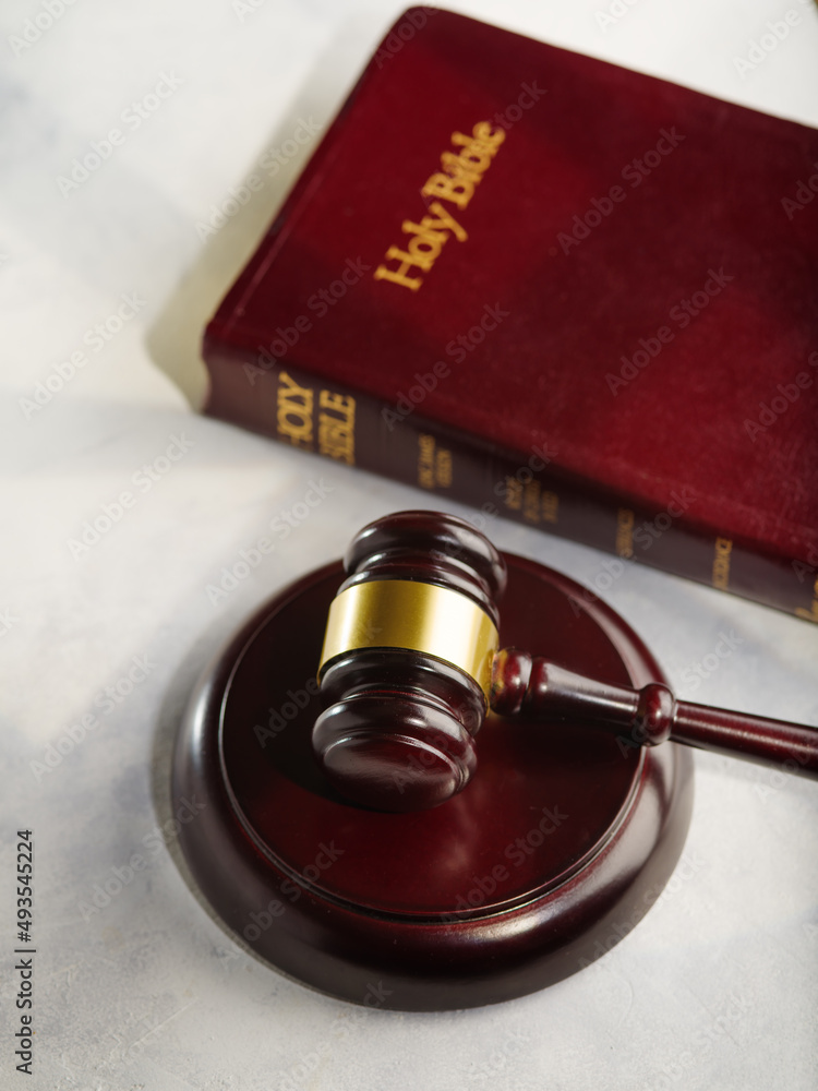 Macro shot. In the foreground is a judge's wooden gavel and a Bible. Isolated on white background. Constitution, independence, rule of law, judicial system of the rule of law.