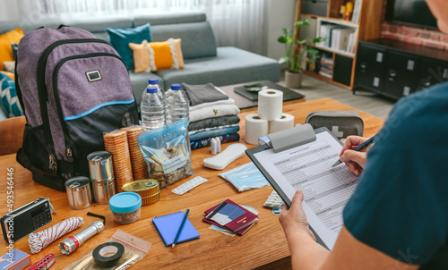 Fotografija Unrecognizable woman doing checklist of emergency backpack in the living room