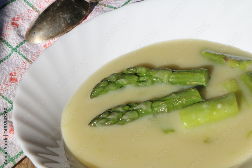 Spargelsuppe, ein Teller mit Spargelsuppe und grünem Spargel, daneben ein Löffel, Spargelrezepte, Suppen, Gemüsesuppe