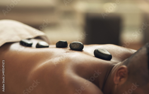 Do yourself and your body a favour. Cropped shot of a man getting a hot stone massage at a spa.