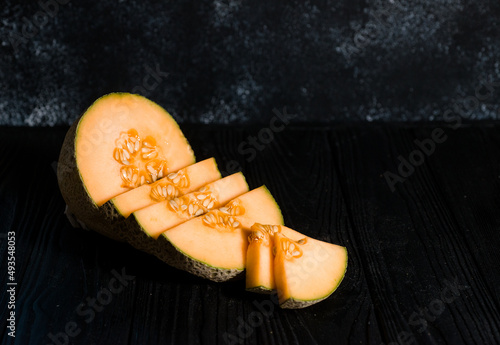 sweet melon on a dark background small delicious beautiful melon, both whole and in pieces and folded for eating