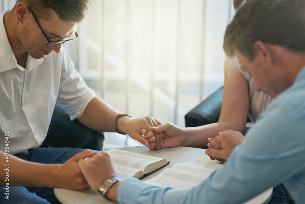 Obraz premium Were praying that success comes along our way. Shot of a group of young businesspeople holding hands while deep in prayer at work.