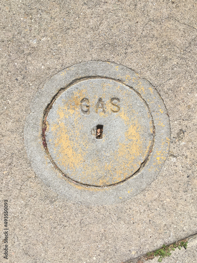 Close-up view of a small concrete cover plate for a gas valve on a city street sidewalk Close-up view of a small concrete cover plate for a gas valve on a city street sidewalk