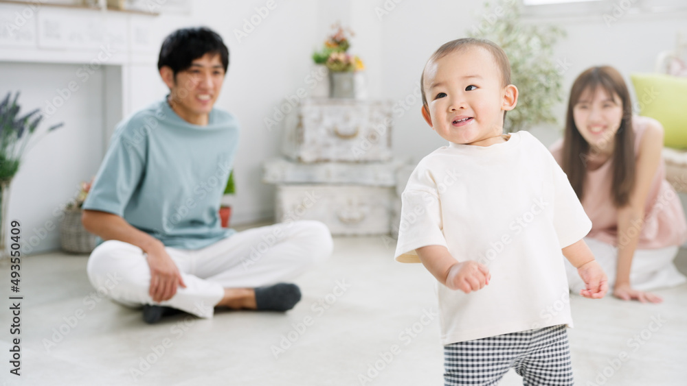 部屋で遊ぶ赤ちゃんとそれを見守る両親 部屋で遊ぶ赤ちゃんとそれを見守る両親