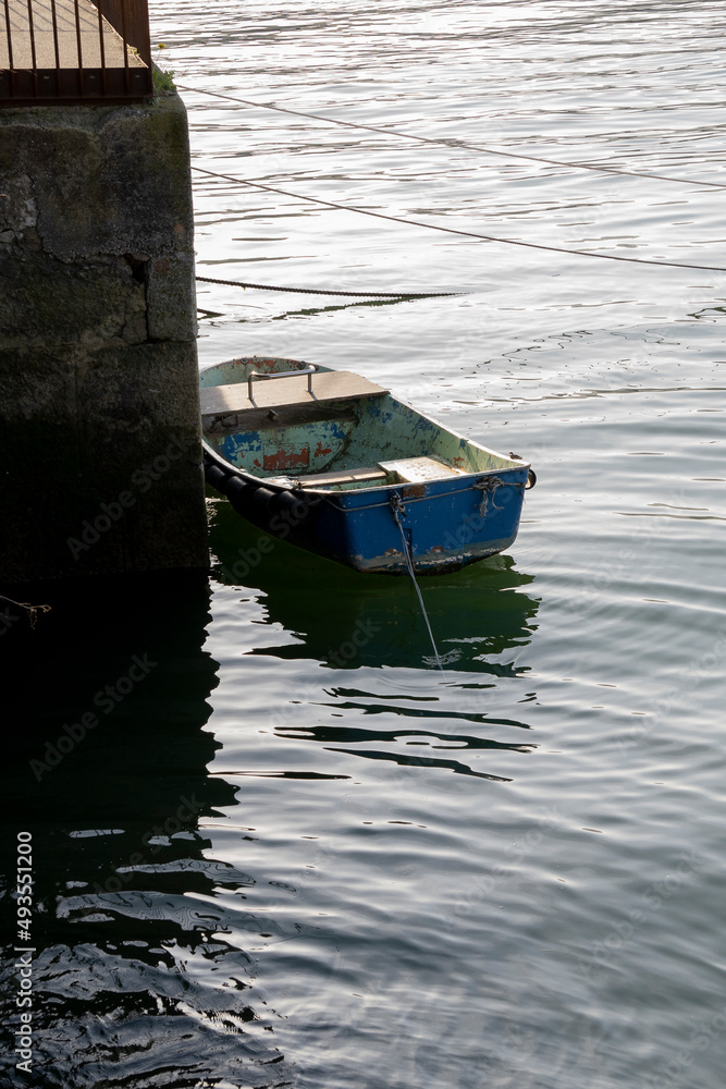 small lonely boat tied to a wall in a river