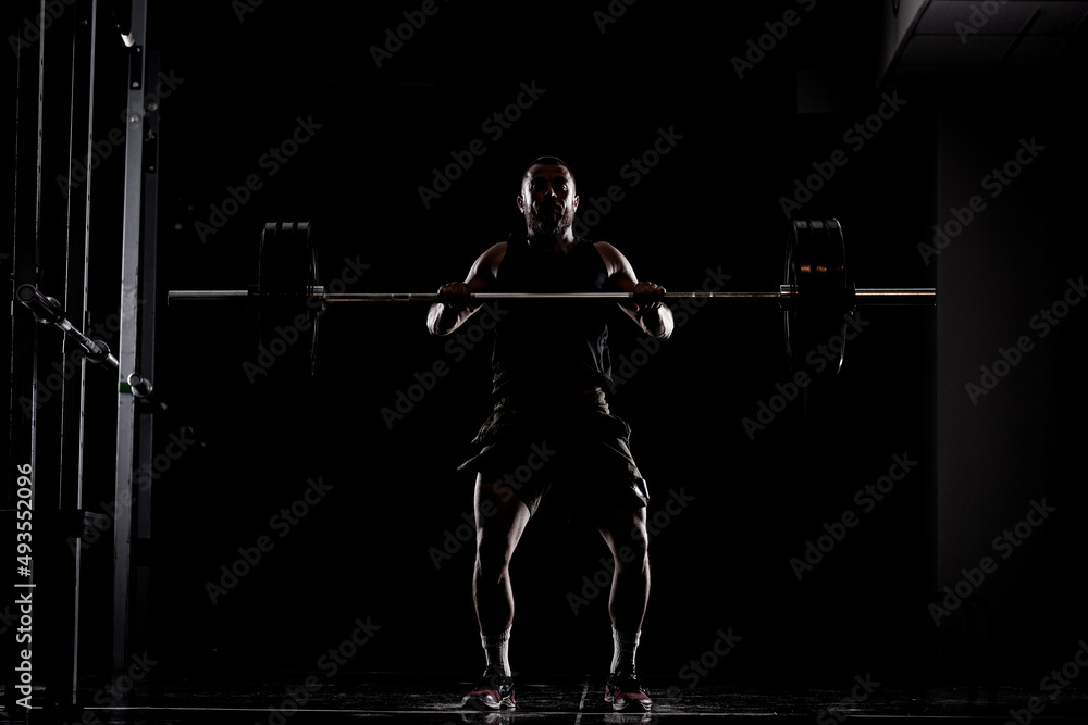Athlete lifting barbell. Silhouette of a muscular man