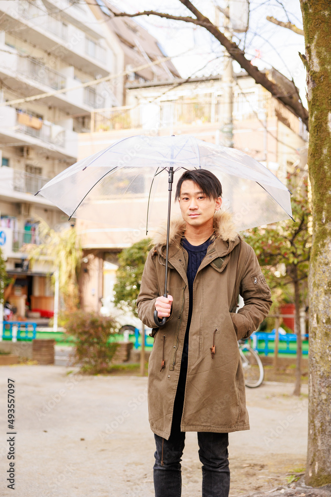 公園で傘をさしている日本人男性 公園で傘をさしている日本人男性
