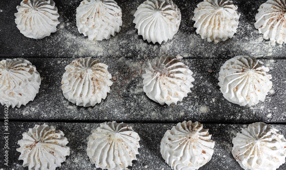 Culinary background with vanilla meringue on dark wooden background, sprinkled with nuts, cocoa and powdered sugar. Still life in style of food. Sweet meringue, delicious and light dessert. Culinary background with vanilla meringue on dark wooden background, sprinkled with nuts, cocoa and powdered sugar. Still life in style of food. Sweet meringue, delicious and light dessert.