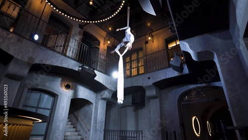 Female aerialist doing spinning candy cane pose on silks in a club. photo