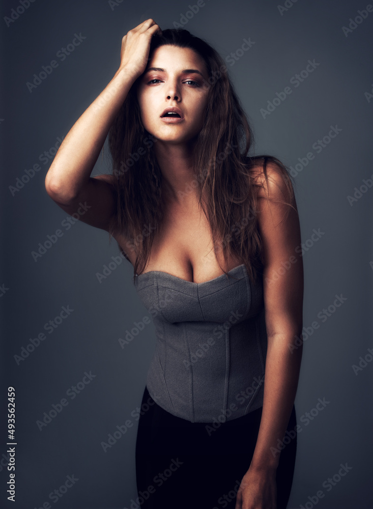 Theres something striking about her beauty. Studio portrait of an attractive young woman posing against a grey background.