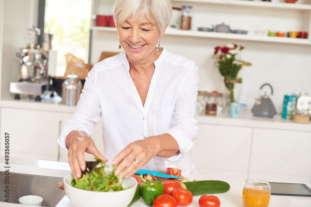 The secret to vitality is a healthy diet. Shot of a senior woman making a salad in her kitchen.