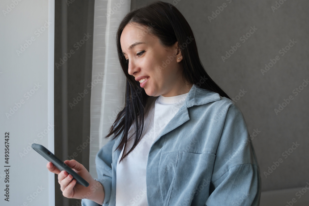 A smiling brunette girl uses a smartphone, makes online purchases in an online store or communicates on a social network. A smiling brunette girl uses a smartphone, makes online purchases in an online store or communicates on a social network.
