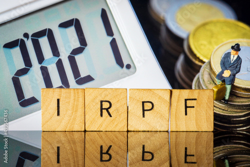 Income Tax Campaign 2021. Taxman sitting on coin stack. IRPF sign Macro photo