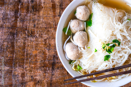 .Noodle and meatballs in a bowl on a wooden table