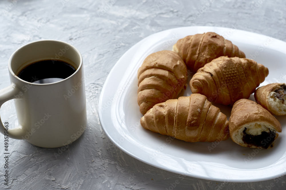a plate of croissants and a cup of coffee on the table