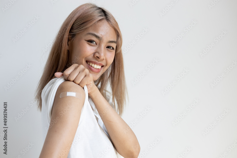 Left-handed asian woman getting vaccinated immunity by vaccine program on her opposite right upper arm, concept of recommended inoculation, vaccinated patient with vaccine booster shot plaster Left-handed asian woman getting vaccinated immunity by vaccine program on her opposite right upper arm, concept of recommended inoculation, vaccinated patient with vaccine booster shot plaster