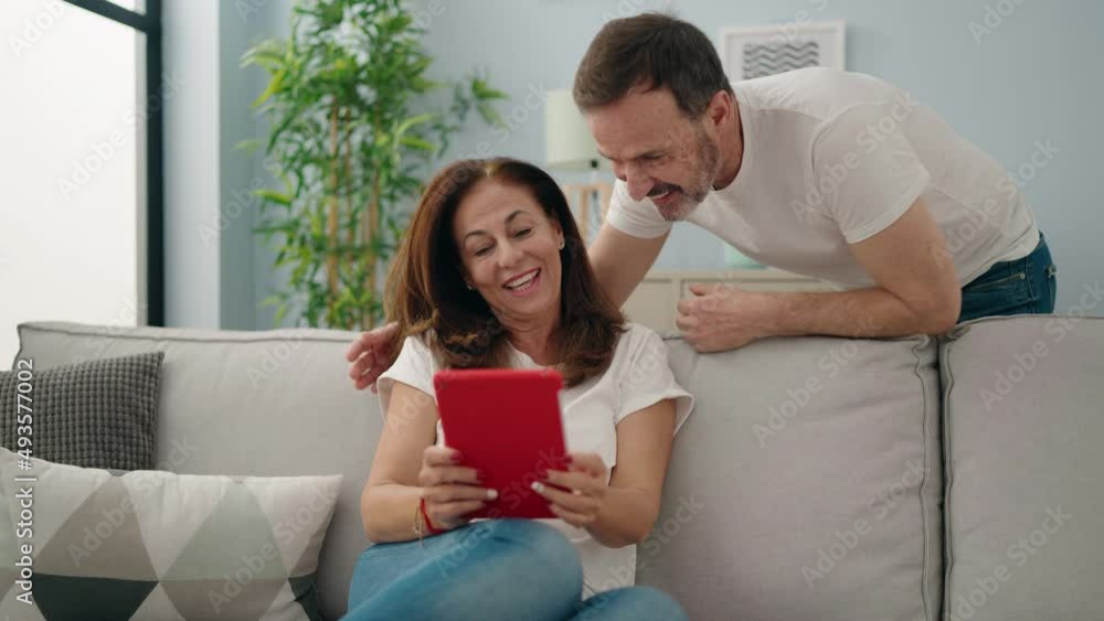 Man and woman couple using touchpad sitting on sofa at home Man and woman couple using touchpad sitting on sofa at home