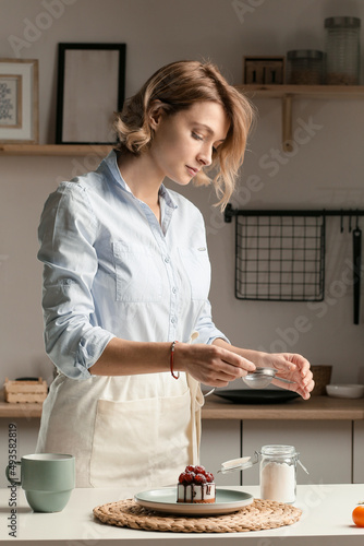 Fototapeta Naklejka Na Ścianę i Meble -  Housewife prepares a cupcake, sprinkles with sugar.