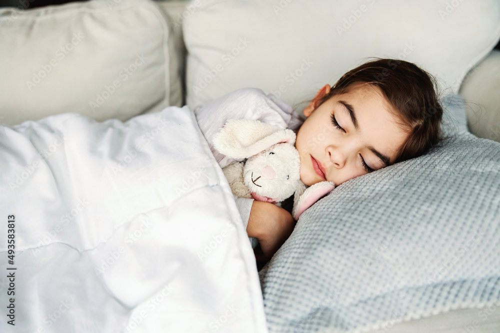 Ill little girl lying on sofa at home, hugging her bunny and sleeping. Ill little girl lying on sofa at home, hugging her bunny and sleeping.