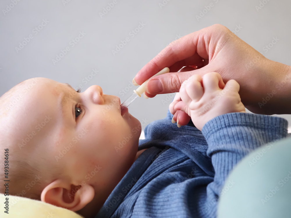mother feeds a newborn baby from a pipette. children's atopic