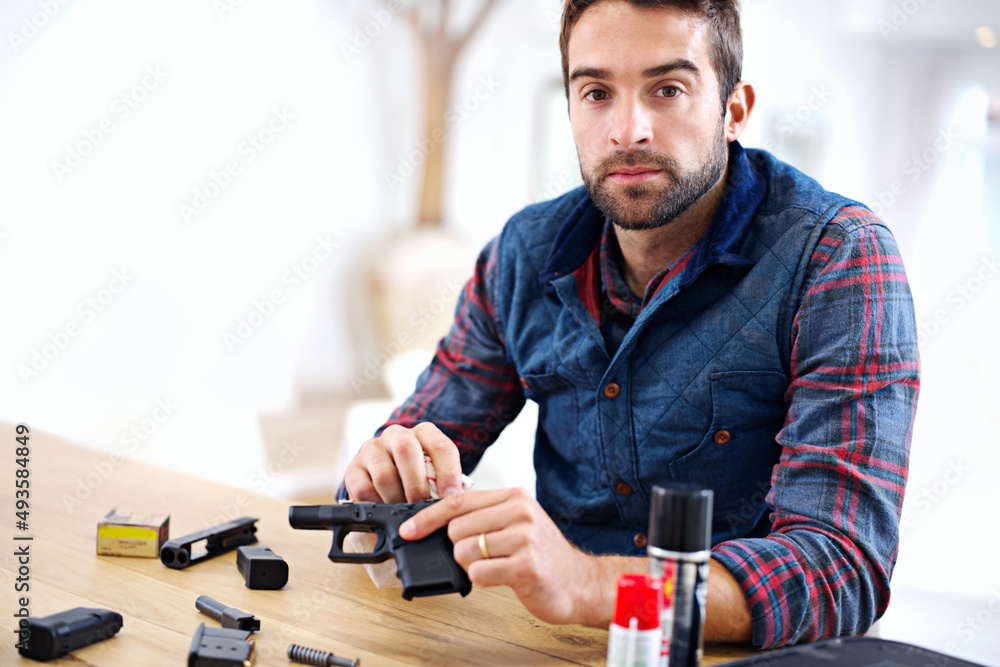 Regular maintenance is essential for every gun owner. A young man cleaning his gun. Regular maintenance is essential for every gun owner. A young man cleaning his gun.
