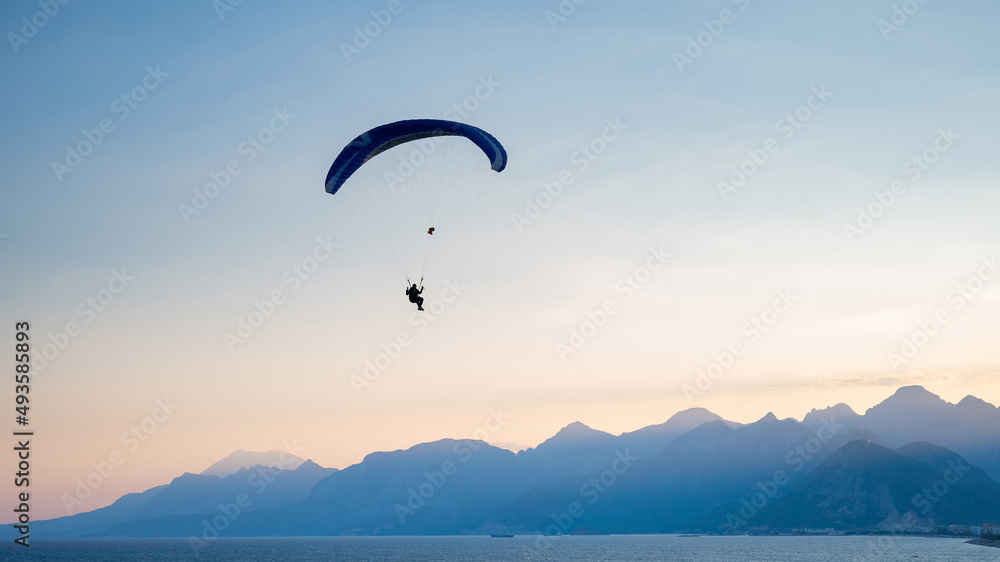 Silhouette of a man on a paraglider flying over the sea at sunset. Silhouette of a man on a paraglider flying over the sea at sunset.
