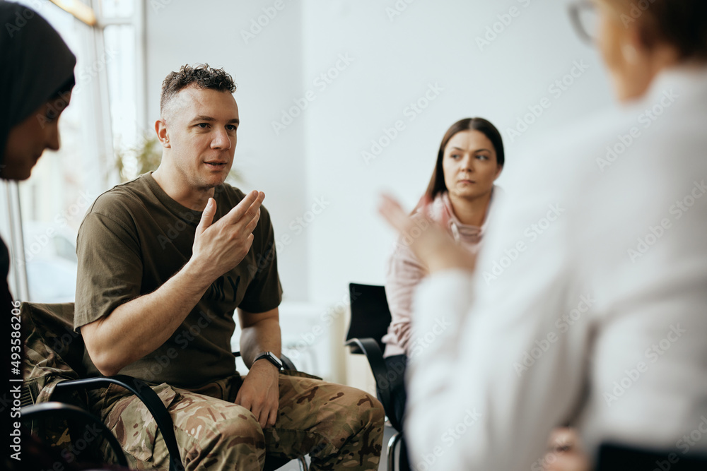 Mid adult veteran shares his story with attenders of group therapy at mental healthcare center. - obrazy, fototapety, plakaty 