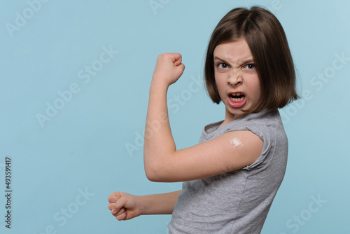 Excited emotional Child shows vaccinated arm after Being Injected Covid-19 Vaccine, motivates to vaccinate against coronavirus to stop epidemic. Health care. Children immunization. Health pass photo