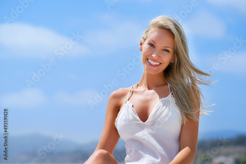 This beach has it all and so does she. Shot of a happy young woman smiling while on the beach. © Yuri A/peopleimages.com
