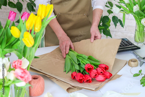 Billede på lærred close-up woman florist packs a bouquet of tulips