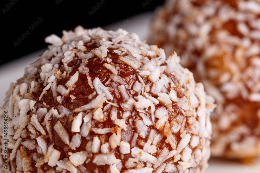 Beautiful sweets with coconut on a white plate on a black background Beautiful sweets with coconut on a white plate on a black background