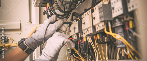 Fotografie, Obraz Electricity and electrical maintenance service, Engineer hand holding AC voltmeter checking electric current voltage at circuit breaker terminal and cable wiring main power distribution board