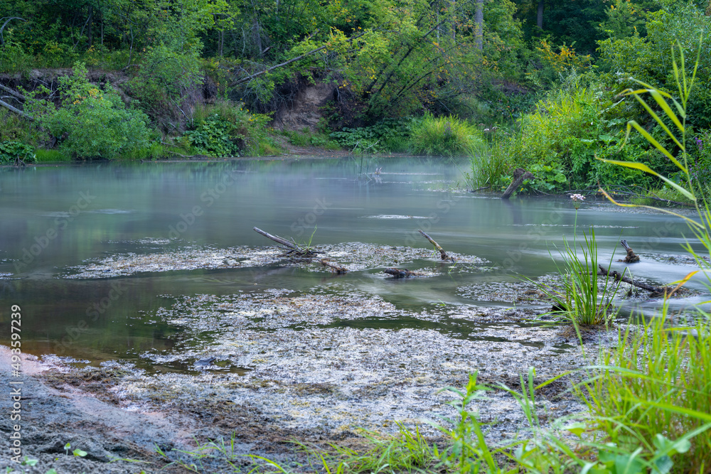 The river is covered with morning fog at sunrise, surrounded by a dense green forest. Wild nature. Active weekend vacations wild nature outdoor. The river is covered with morning fog at sunrise, surrounded by a dense green forest. Wild nature. Active weekend vacations wild nature outdoor.